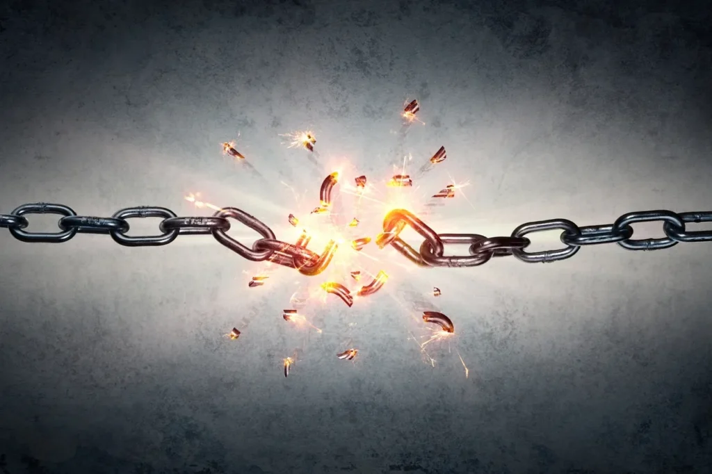 Chain breaking apart with sparks and fragments flying.